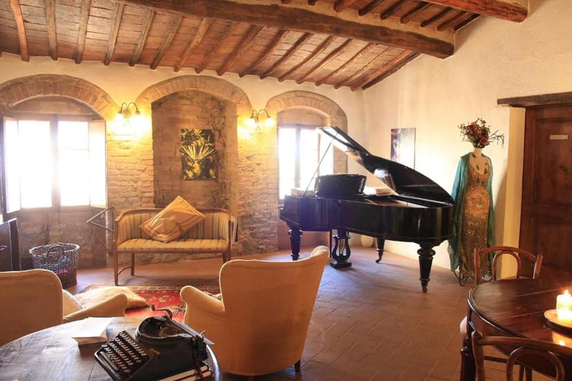 Interior room with exposed wood beams, brick arches, grand piano, and vintage typewriter.