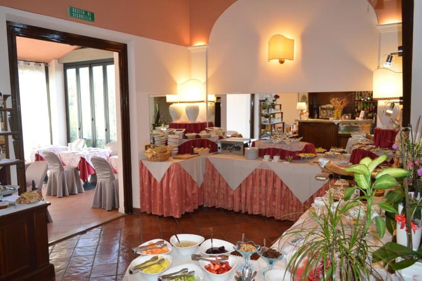 Buffet breakfast setup with fruit, pastries, and dining area visible through doorway.
