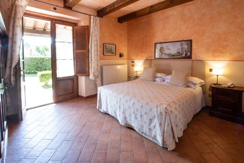 Bedroom with terracotta floor, orange walls, and open wooden doors leading to a garden.