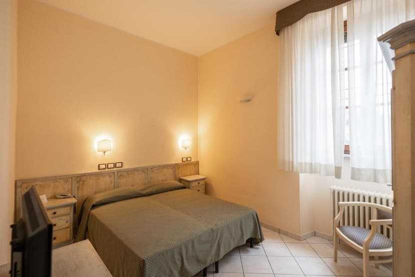 Bedroom in Villa Santa Margherita with double bed, bedside tables, and sheer white curtains.