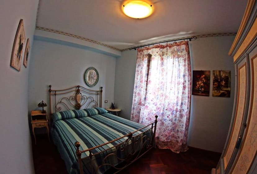 Bedroom with iron bed, striped bedding, floral curtains, and wood floor