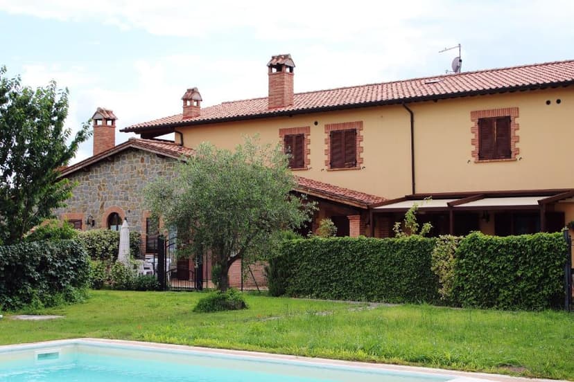 Swimming pool in front of a Tuscan-style villa with stone accents and green lawn