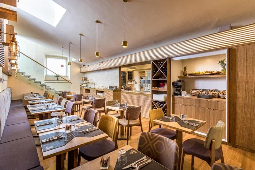 Dining area with set tables, wood accents, and a bright staircase leading to a skylight.