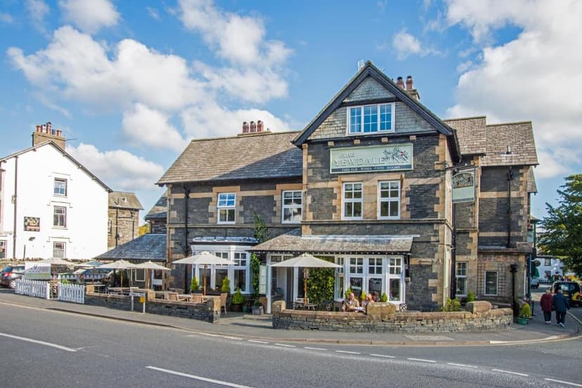 The Yewdale Inn and Hotel in Coniston Village with outdoor seating under umbrellas.