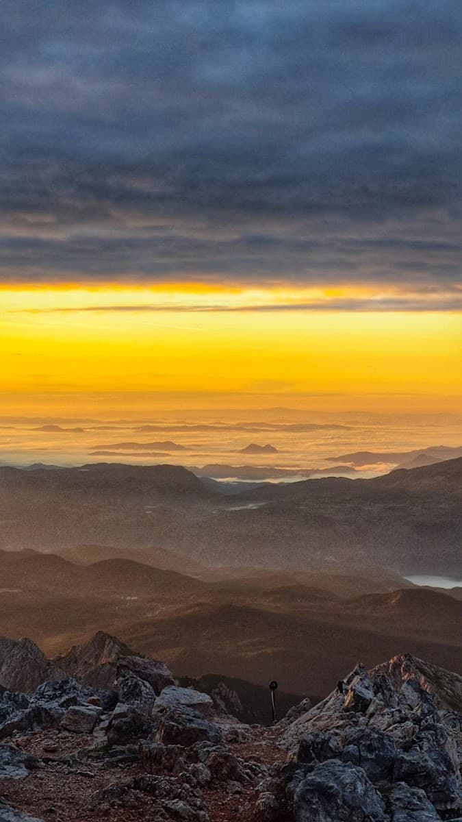 Mountain summit view at sunrise over layered peaks shrouded in fog and mist