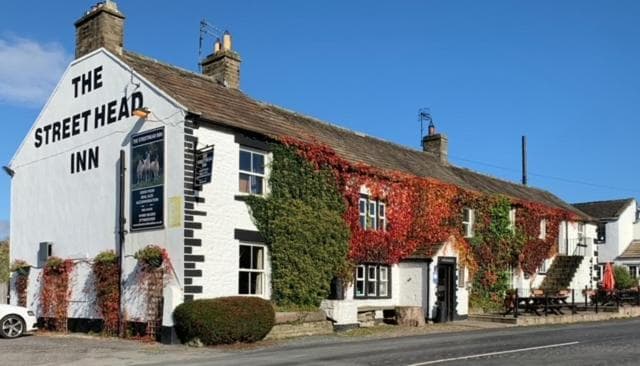 The Street Head Inn building with white walls and autumn ivy under a clear blue sky