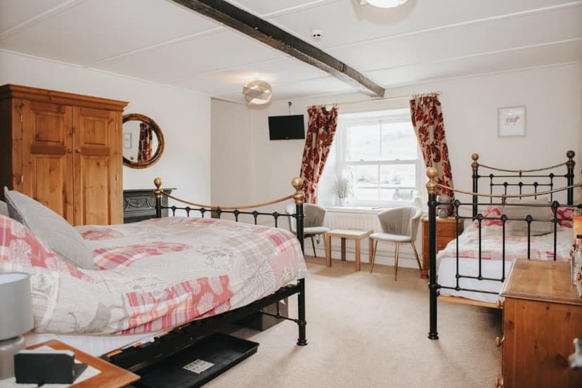 Bedroom with two metal-frame beds, wooden wardrobe, and window view