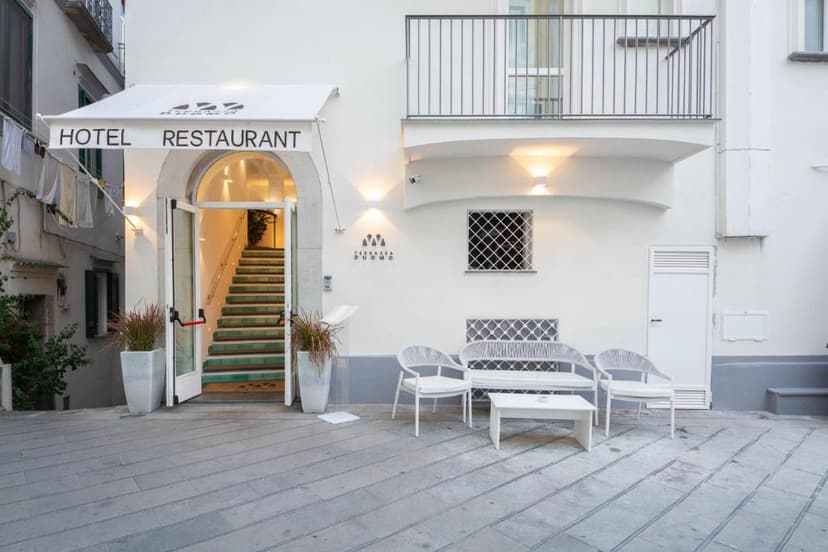 Hotel and restaurant entrance with white outdoor seating area and stairs leading inside.