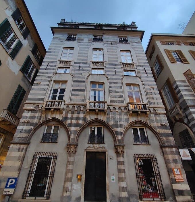 Historic building with horizontal stone stripes and arched ground floor windows in a European city.