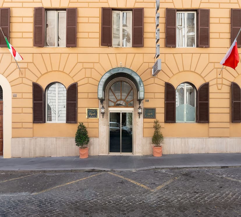 Hotel Virgilio entrance with arched windows, brown shutters, and Italian and Polish flags flying.
