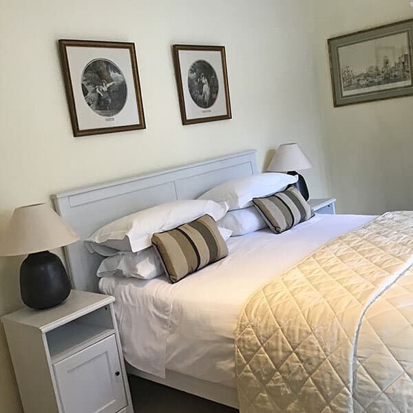 Bedroom with white bedding, striped pillows, and framed artwork above light blue headboard.