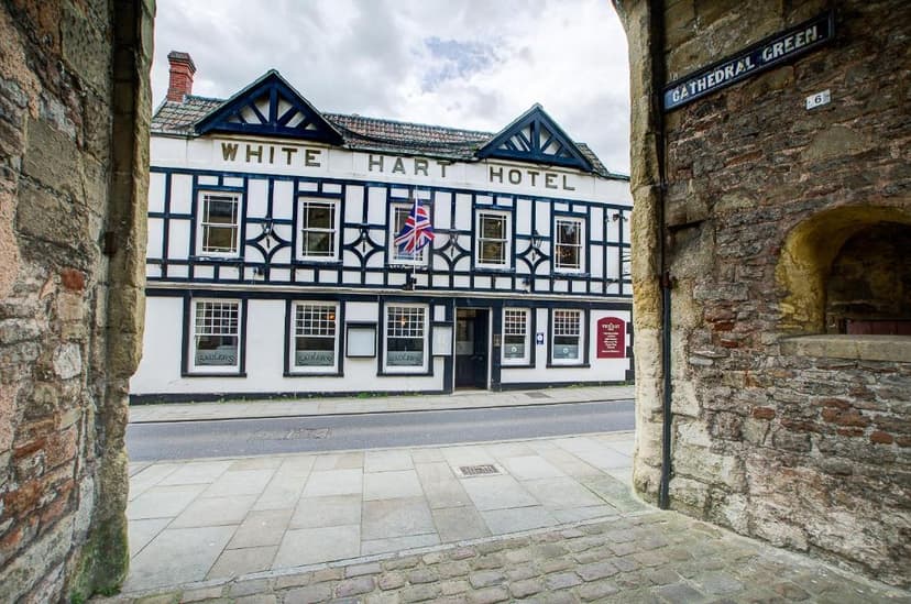 White Hart Hotel with Tudor-style facade viewed through stone archway on Cathedral Green.