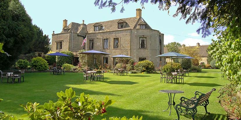 Stone hotel with garden seating and blue umbrellas on a sunny day