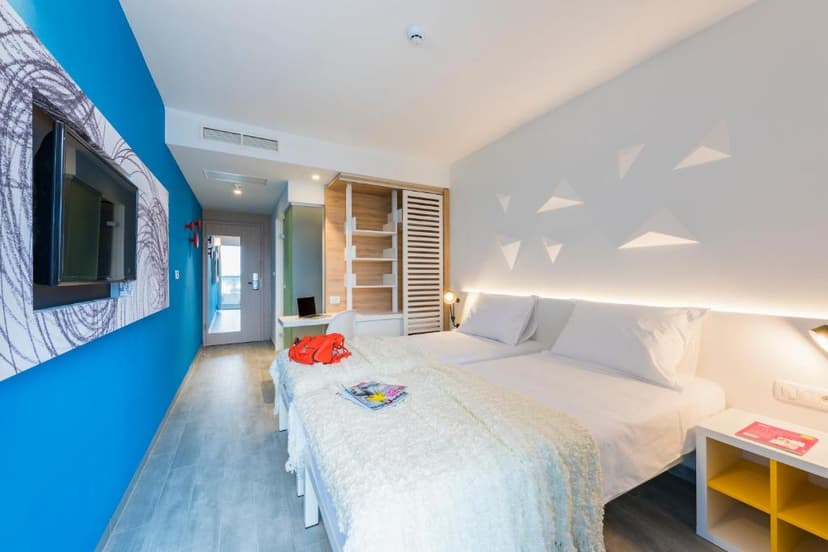 Twin beds in modern hotel room with bright blue accent wall and built-in shelving near Hvar Bayhill Hotel.