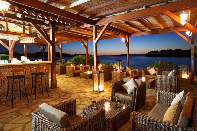 Outdoor wicker lounge bar with stone floor overlooking the sea at twilight, Mljet.