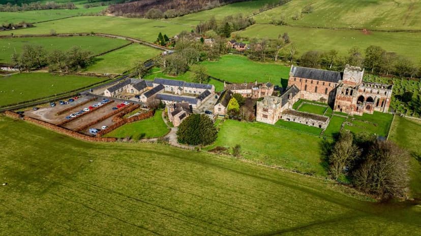 Aerial view of Abbey Farmhouse complex surrounded by green fields and rolling hills.