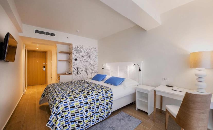 Modern hotel room with nautical map wall art, blue bedding, and wooden floors at Amadria Park Beach Hotel Jure.