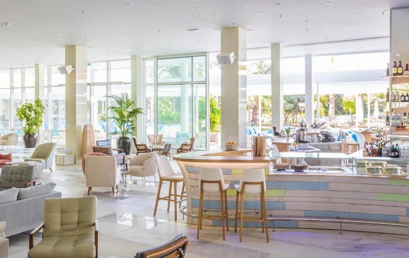 Bright hotel lobby bar with modern seating and large windows overlooking greenery at Amadria Park Beach Hotel Jure.