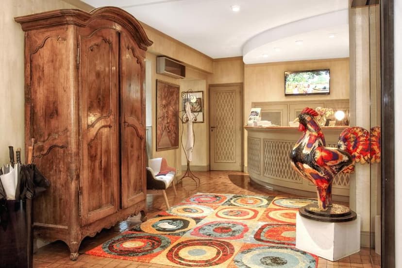 Hotel reception area with antique wardrobe, colorful rug, and large rooster statue near Le Pont de L'Ouysse.