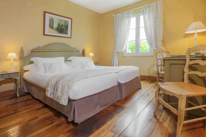 Bedroom with twin beds, yellow walls, wooden floor, and window view at Le Pont de L'Ouysse.