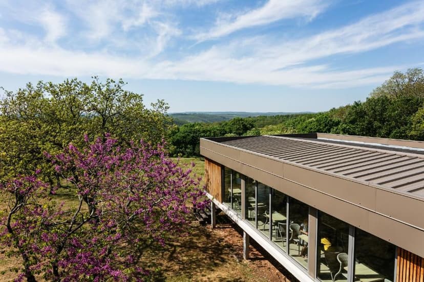 Modern building with large windows overlooking lush green hills under a blue sky in Rocamadour.