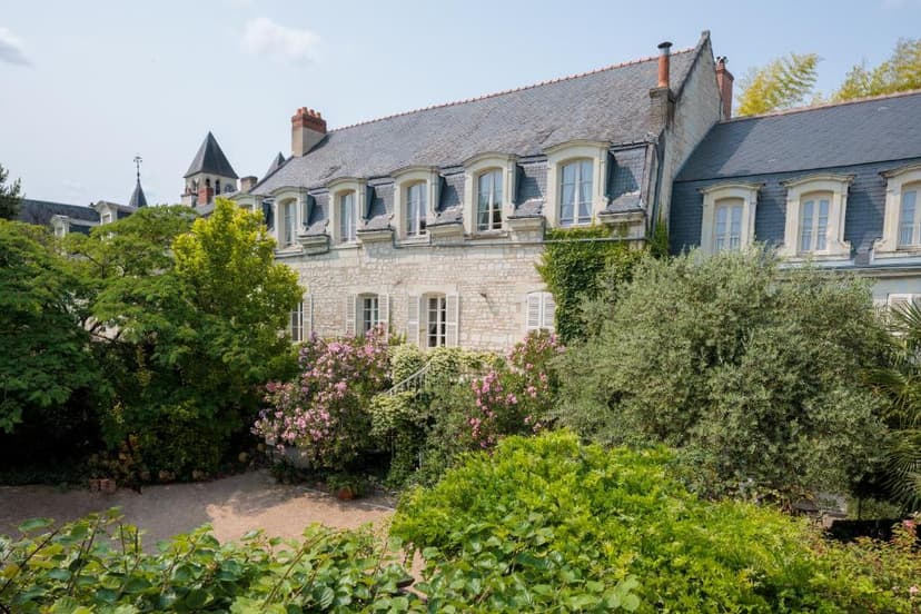 Stone building with slate roof viewed over lush garden and pink flowering bushes, Hôtel Diderot.