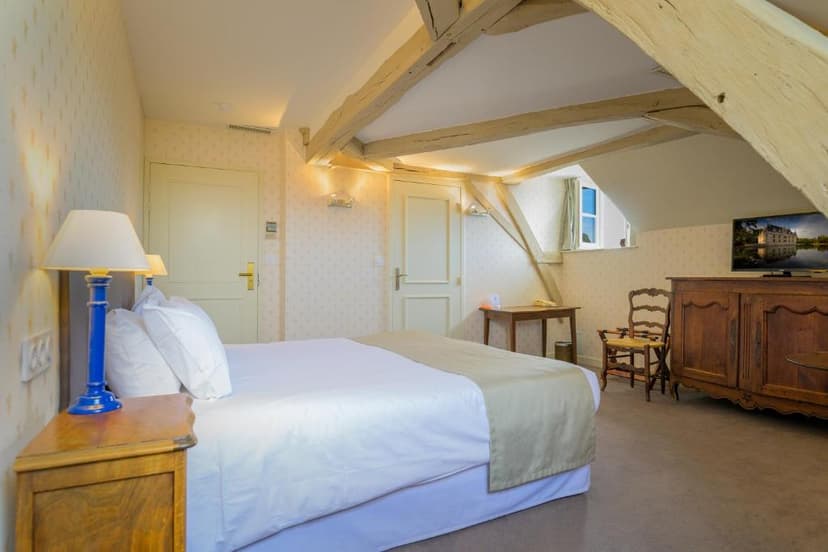 Bedroom in Hôtel Le Grand Monarque with exposed wooden beams and antique furniture.