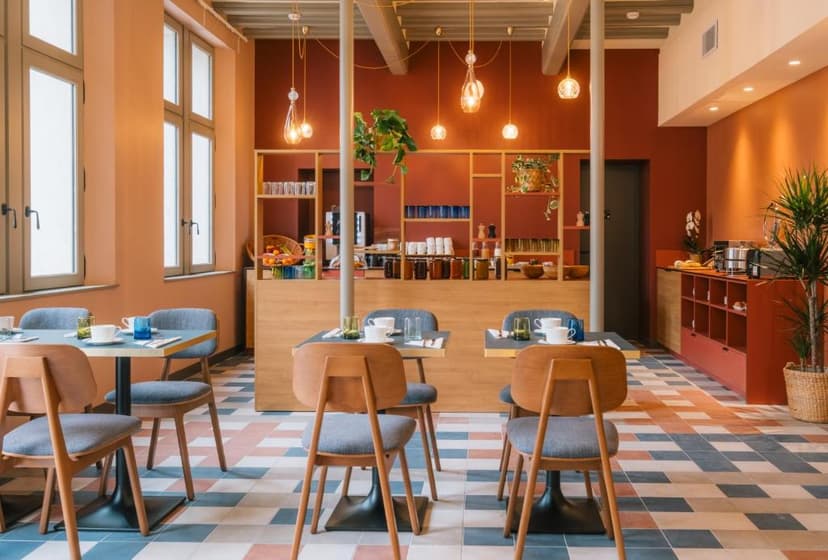 Dining area with wooden chairs, small tables, and a buffet counter against terracotta walls.