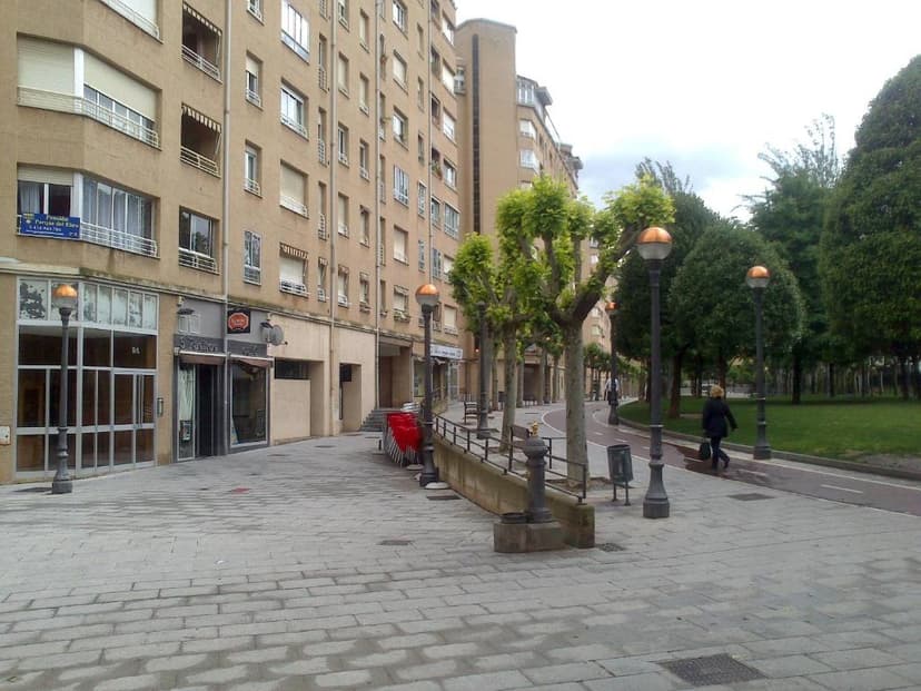 Sidewalk with lampposts next to a park and apartment buildings in Logroño.