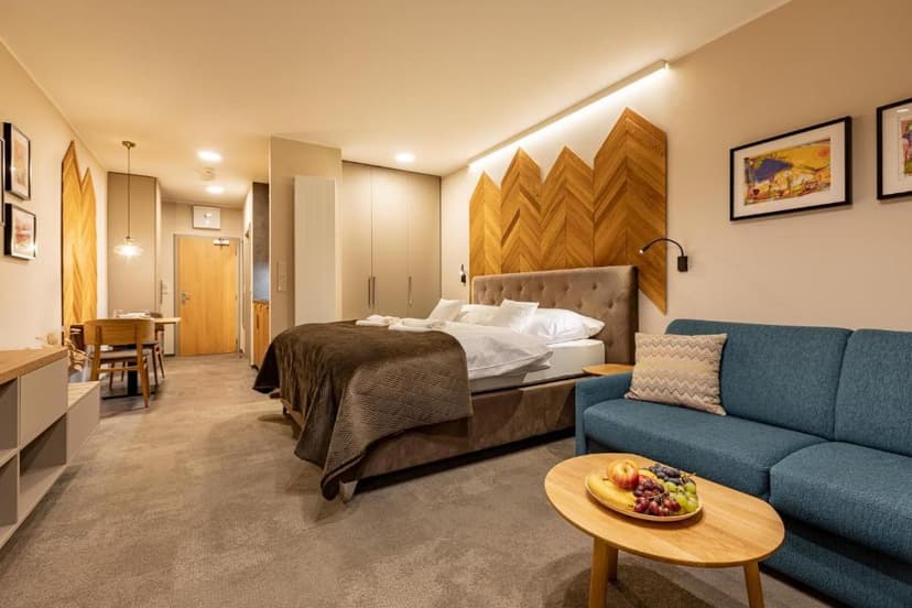 Hotel suite with large bed, blue sofa, and wooden chevron headboard accent