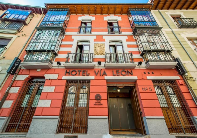 Hotel Vía León facade with orange and white stripes and enclosed glass balconies.