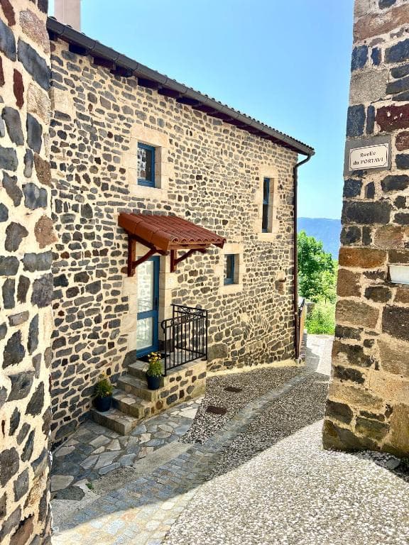 Stone building entrance on Ruelle du Portavi, narrow cobbled alleyway with mountains visible.