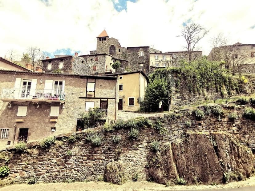 Stone houses built on a hillside with a church tower in Auberge de Chanteuges.