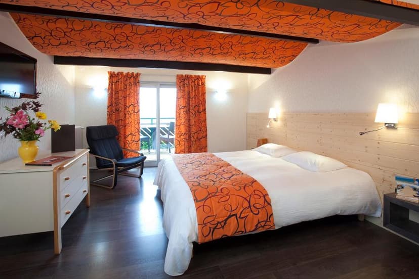 Hotel room with orange patterned ceiling, white bedding, and balcony access.