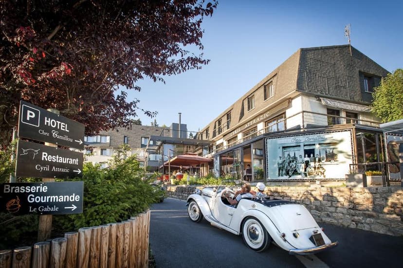 White vintage convertible arriving at Logis Hôtel et Spa Chez Camillou with directional signs.