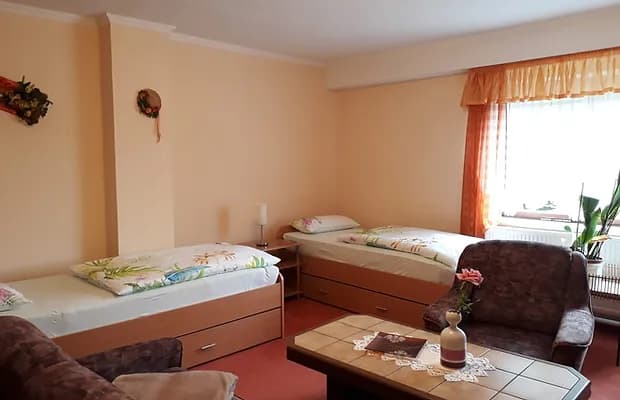 Twin guest room in Gastepension Straubel with two beds, armchair, and window view.