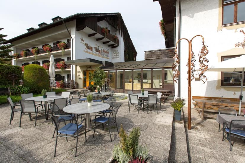 Hotel Gasthof am Wald outdoor patio with tables, chairs, and mural on building facade.