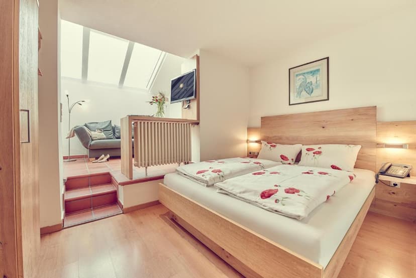 Twin beds with poppy print duvets in a bright room with a raised seating area.