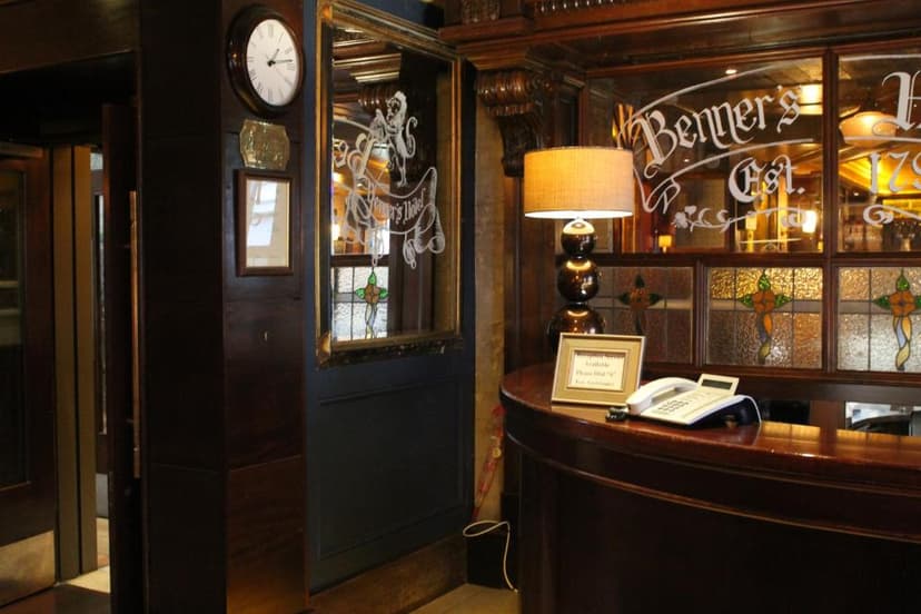 Hotel reception desk with dark wood, lamp, phone, and "Benners Hotel" etched glass.