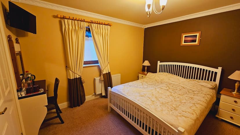 Cozy guest room with white wood bed, yellow and brown walls, and window with heavy curtains