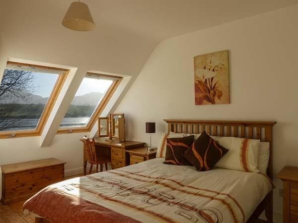 Bedroom in O'Connors Guesthouse with sloped windows showing mountain and water view