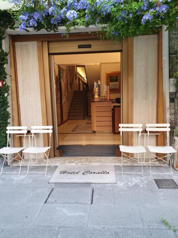 Hotel Corallo entrance with white metal chairs and blue flowers above doorway