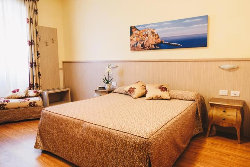 Bedroom with double bed, patterned linens, and painting of colorful cliffside village.