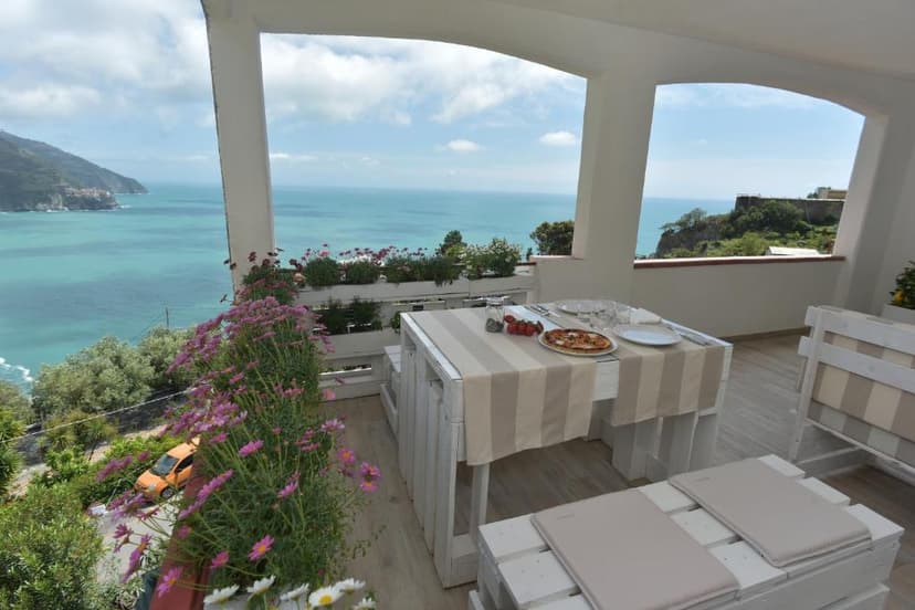 Dining terrace with pizza overlooking turquoise Mediterranean coastline and green cliffs