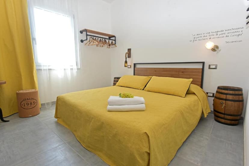 Bedroom with yellow bedding, white towels, grapes, and a wooden barrel nightstand.