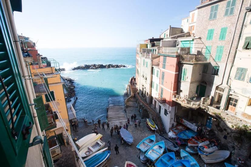 Boats pulled ashore near colorful buildings overlooking turquoise Mediterranean sea
