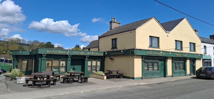 Central House pub with green trim and outdoor picnic tables under a blue sky.