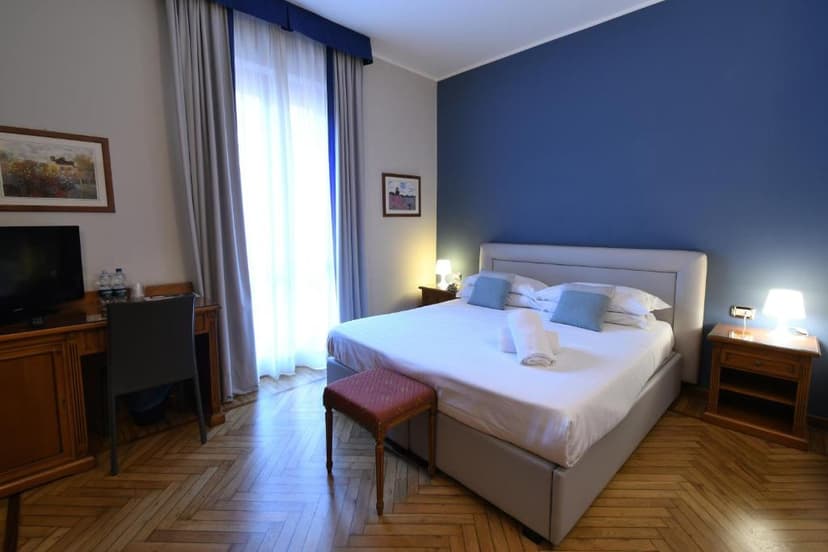 Hotel room with white bedding, blue accent wall, and parquet flooring, Hotel Cavour