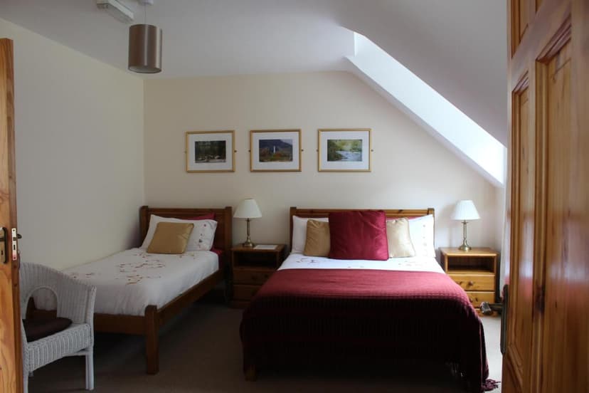Twin bedroom with wooden beds, red bedding, and sloped ceiling in Riversdale House.