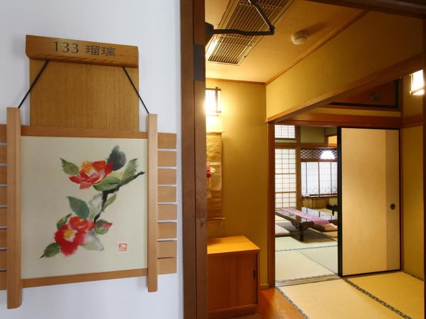 Japanese inn hallway with camellia art and view into tatami room with low table